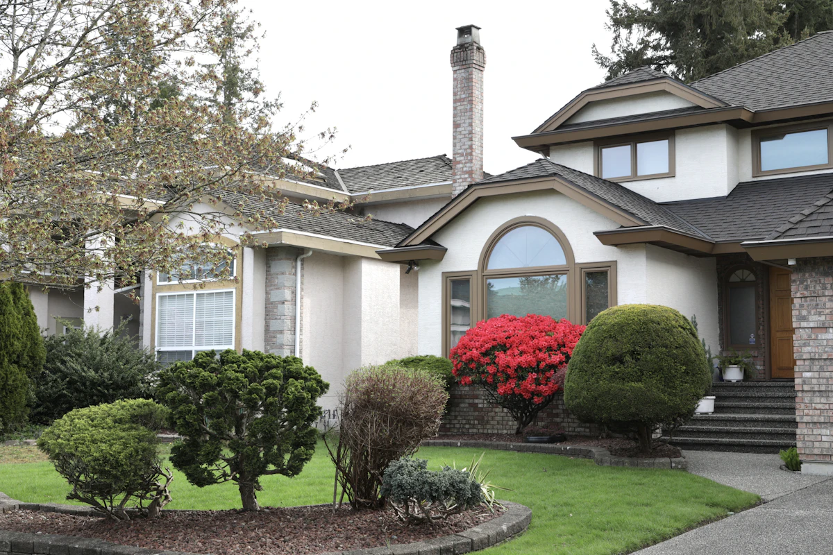 Residential yard with shaped shrubs, flowering plants, and defined beds
