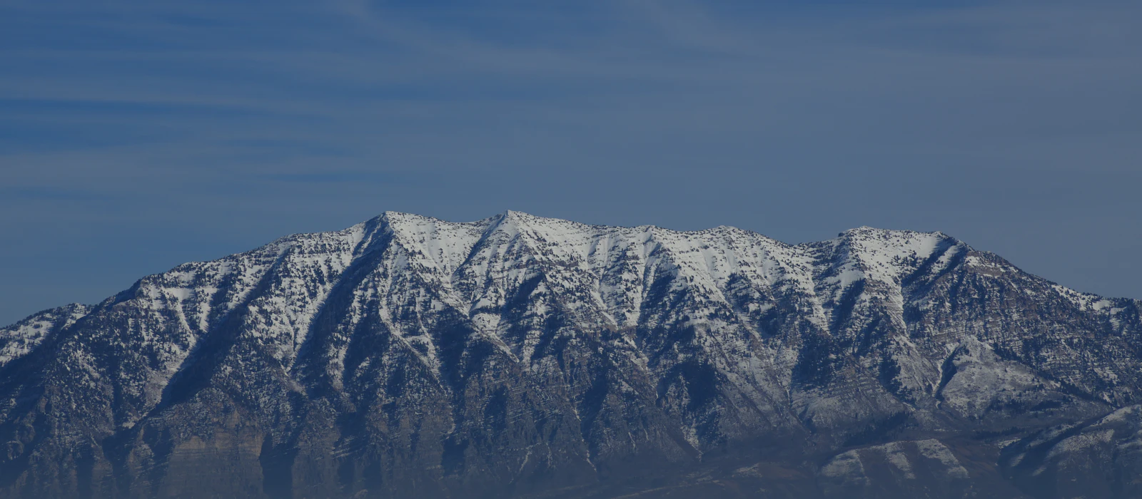 Snow-capped Wasatch mountain range under a blue sky